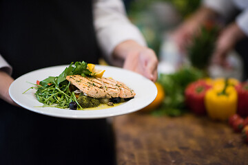 Image showing Chef hands holding dish of fried Salmon fish fillet