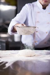 Image showing chef sprinkling flour over fresh pizza dough