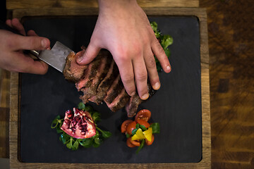 Image showing top view of Chef hands serving beef steak