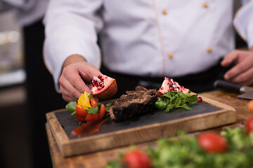 Image showing closeup of Chef hands serving beef steak