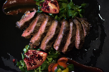 Image showing Juicy slices of grilled steak on wooden board