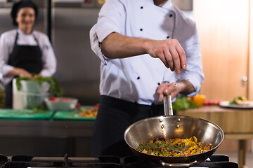 Image showing chef putting spices on vegetables in wok