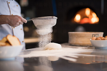 Image showing chef sprinkling flour over fresh pizza dough