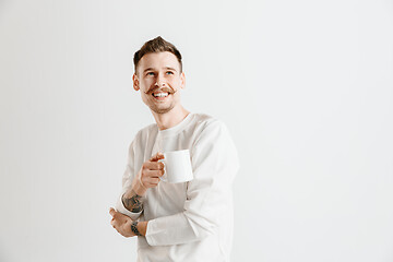 Image showing Taking a coffee break. Handsome young man holding coffee cup while standing against gray background