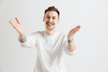 Image showing The happy businessman standing and smiling against gray background.