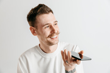 Image showing Indoor portrait of attractive young man holding smartphone