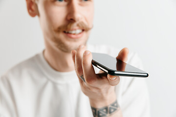 Image showing Indoor portrait of attractive young man holding smartphone