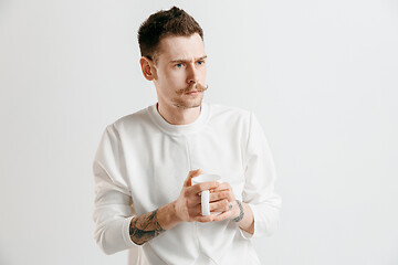 Image showing Taking a coffee break. Handsome young man holding coffee cup while standing against gray background