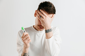 Image showing Upset man looking in pregnancy test. Frustrated model