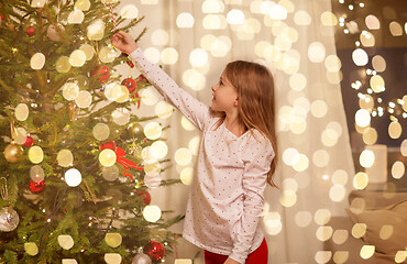 Image showing happy girl in red dress decorating christmas tree