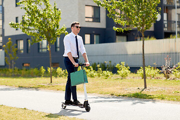 Image showing businessman with shopping bag riding scooter