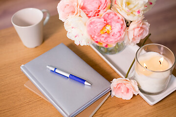 Image showing burning candle and flower bunch on wooden table