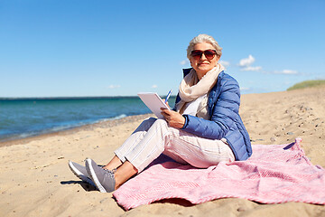 Image showing senior woman writing to notebook on summer beach