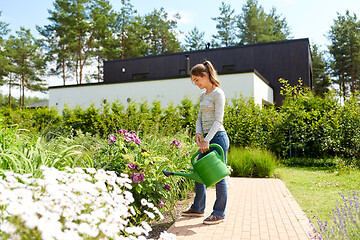 Image showing young woman watering flowers at garden