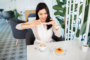 Image showing woman photographing coffee by smartphone at cafe