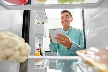 Image showing man making list of necessary food at home fridge