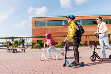 Image showing happy school children with mother riding scooters