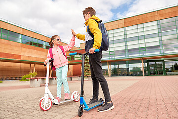 Image showing happy school children with backpacks and scooters