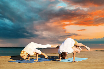 Image showing couple making yoga side crane pose outdoors