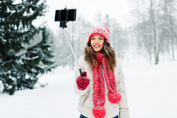 Image showing young woman taking selfie by monopod in winter