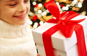 Image showing happy girl with christmas gift over festive lights