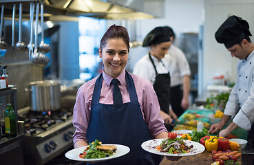 Image showing young waitress showing dishes of tasty meals