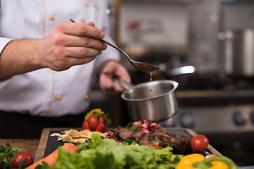 Image showing Chef hand finishing steak meat plate