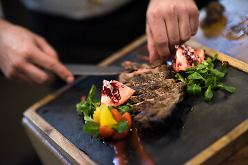 Image showing closeup of Chef hands serving beef steak