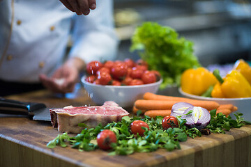 Image showing Chef putting salt on juicy slice of raw steak