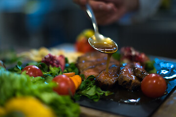 Image showing Chef hand finishing steak meat plate