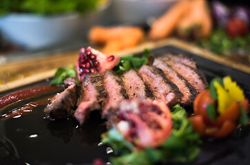 Image showing Juicy slices of grilled steak on wooden board