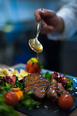 Image showing Chef hand finishing steak meat plate