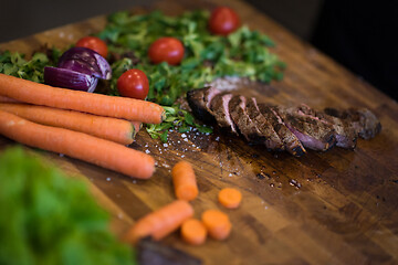 Image showing Juicy slices of grilled steak on wooden board