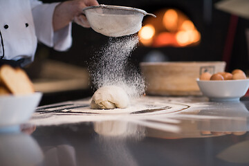 Image showing chef sprinkling flour over fresh pizza dough