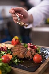 Image showing Chef hand finishing steak meat plate