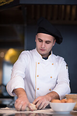 Image showing young chef preparing dough for pizza