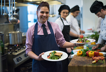 Image showing young waitress showing dishes of tasty meals