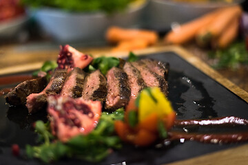 Image showing Juicy slices of grilled steak on wooden board