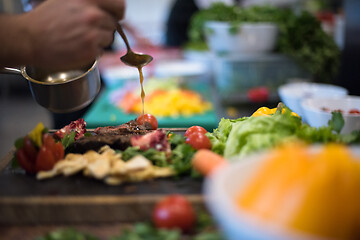 Image showing Chef hand finishing steak meat plate