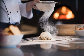 Image showing chef sprinkling flour over fresh pizza dough