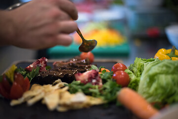 Image showing Chef hand finishing steak meat plate