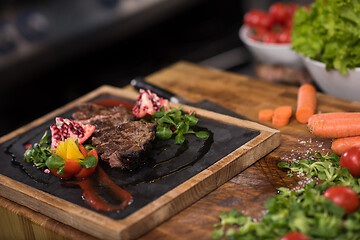 Image showing Juicy slices of grilled steak on wooden board