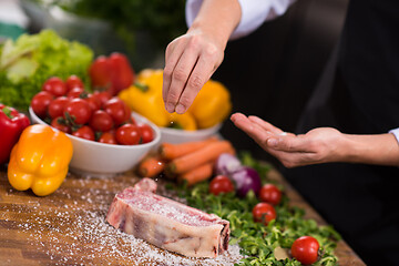 Image showing Chef putting salt on juicy slice of raw steak