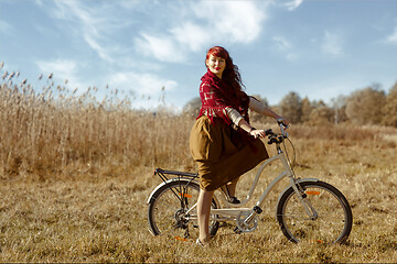 Image showing Pretty girl riding bicycle in field