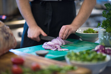 Image showing Chef  hands cutting the onion with knife