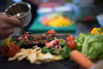 Image showing Chef hand finishing steak meat plate