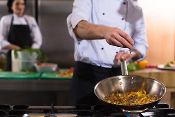 Image showing chef putting spices on vegetables in wok