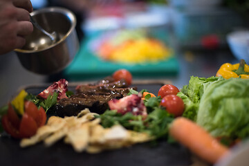 Image showing Chef hand finishing steak meat plate