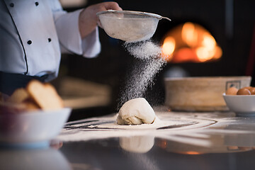 Image showing chef sprinkling flour over fresh pizza dough