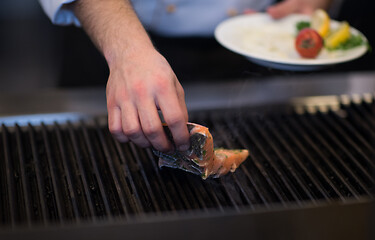 Image showing chef hands cooking grilled salmon fish